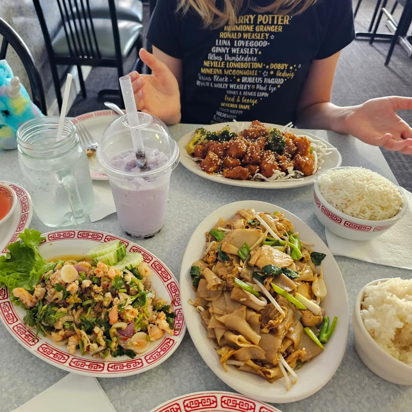 Table laden with Crystal Garden's Asian-fusion dishes, including noodles, rice, and a purple drink.