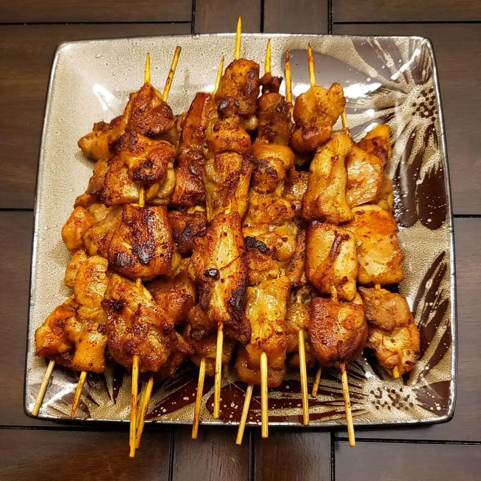 A plate of golden-brown chicken satay skewers, perfectly grilled, from Crystal Garden's Asian-fusion menu.